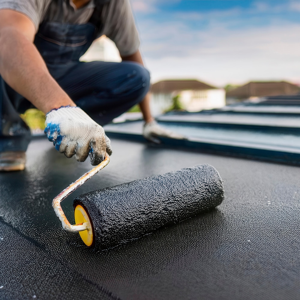 Étanchéité de Toiture : Application de Revêtement au Rouleau Ouvrier appliquant un revêtement d'étanchéité noir au rouleau sur une toiture pour assurer son imperméabilisation.